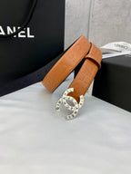 Tan-orange leather belt with embossed strap texture and circular logo buckle.
