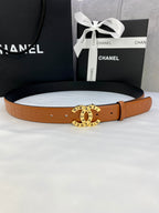 Tan-orange leather belt with circular logo buckle and adjustable holes.