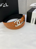 Tan-orange leather belt with circular logo buckle centered on the band.