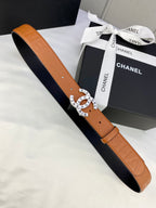 Tan-orange leather belt with embossed pattern, circular logo buckle on strap end.