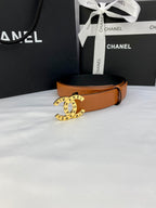 Tan-orange leather belt with circular logo buckle and buckle facing upward.