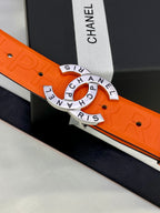 Chanel belt close-up: orange embossed strap and gold-tone circular logo buckle