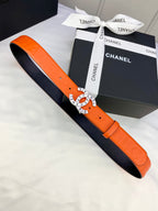 Chanel belt with orange strap and black underside, laid flat beside box