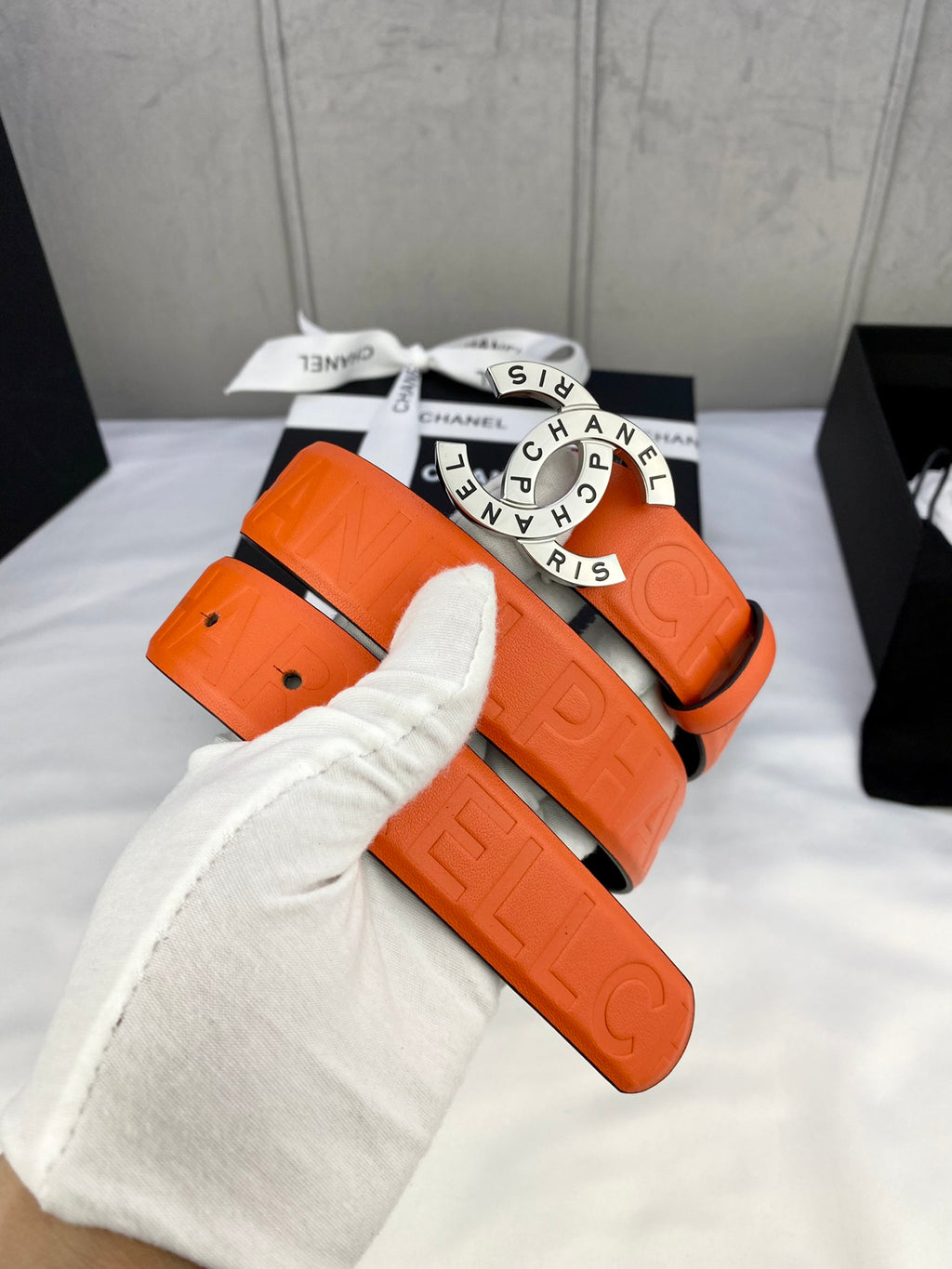 Chanel belt with orange strap and gold-tone logo buckle, wrapped with pouch