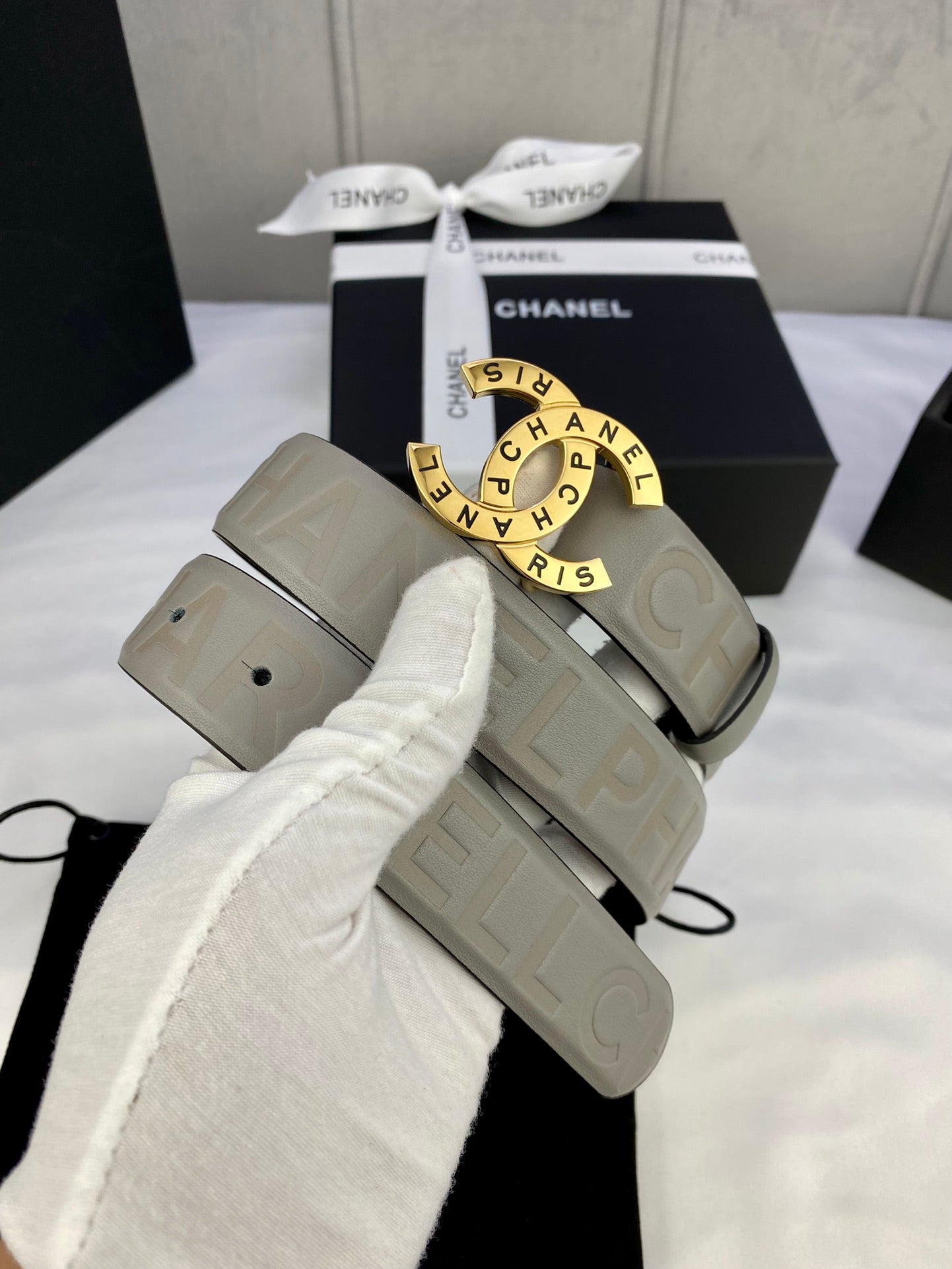 Light beige Chanel belt with circular logo buckle and embossed strap, in gift box