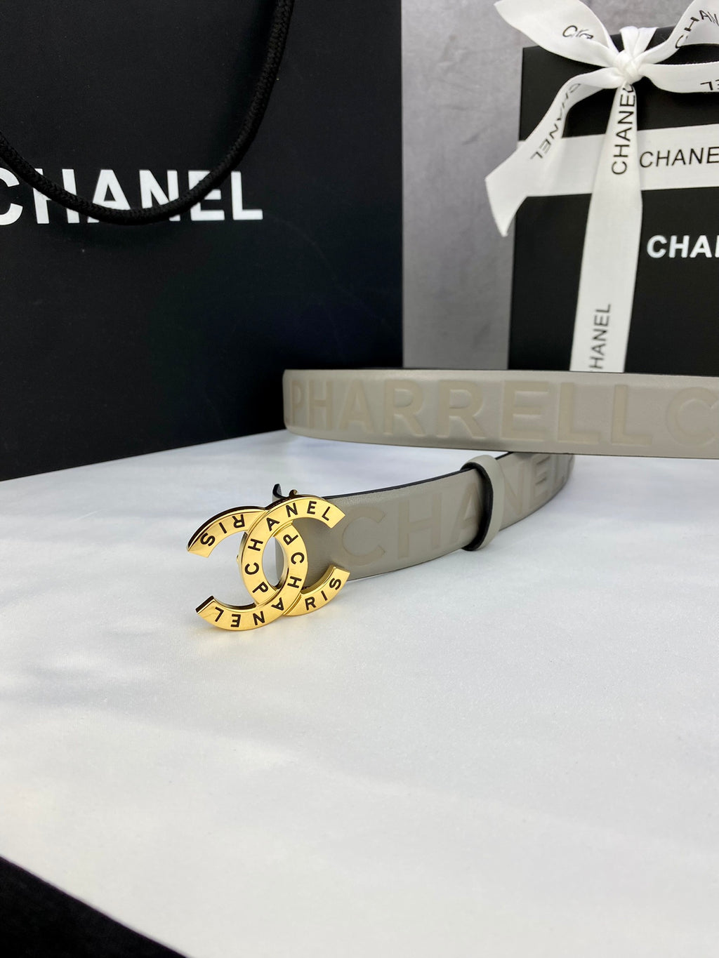 Beige Chanel belt with circular logo buckle and embossed strap, laid on white