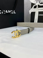 Beige Chanel belt with circular logo buckle and embossed strap, laid on white