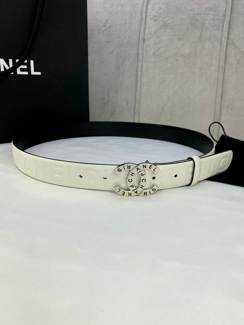 White Chanel belt with circular gold logo buckle, strap holes and embossed lettering