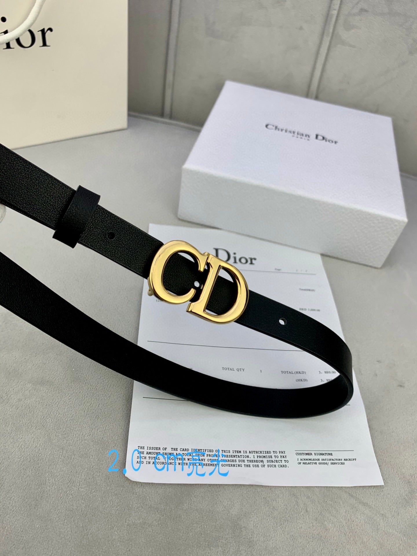 Black leather belt with gold-tone CD buckle, angled view