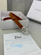 Tan leather belt with CD buckle, laid across Dior packaging card