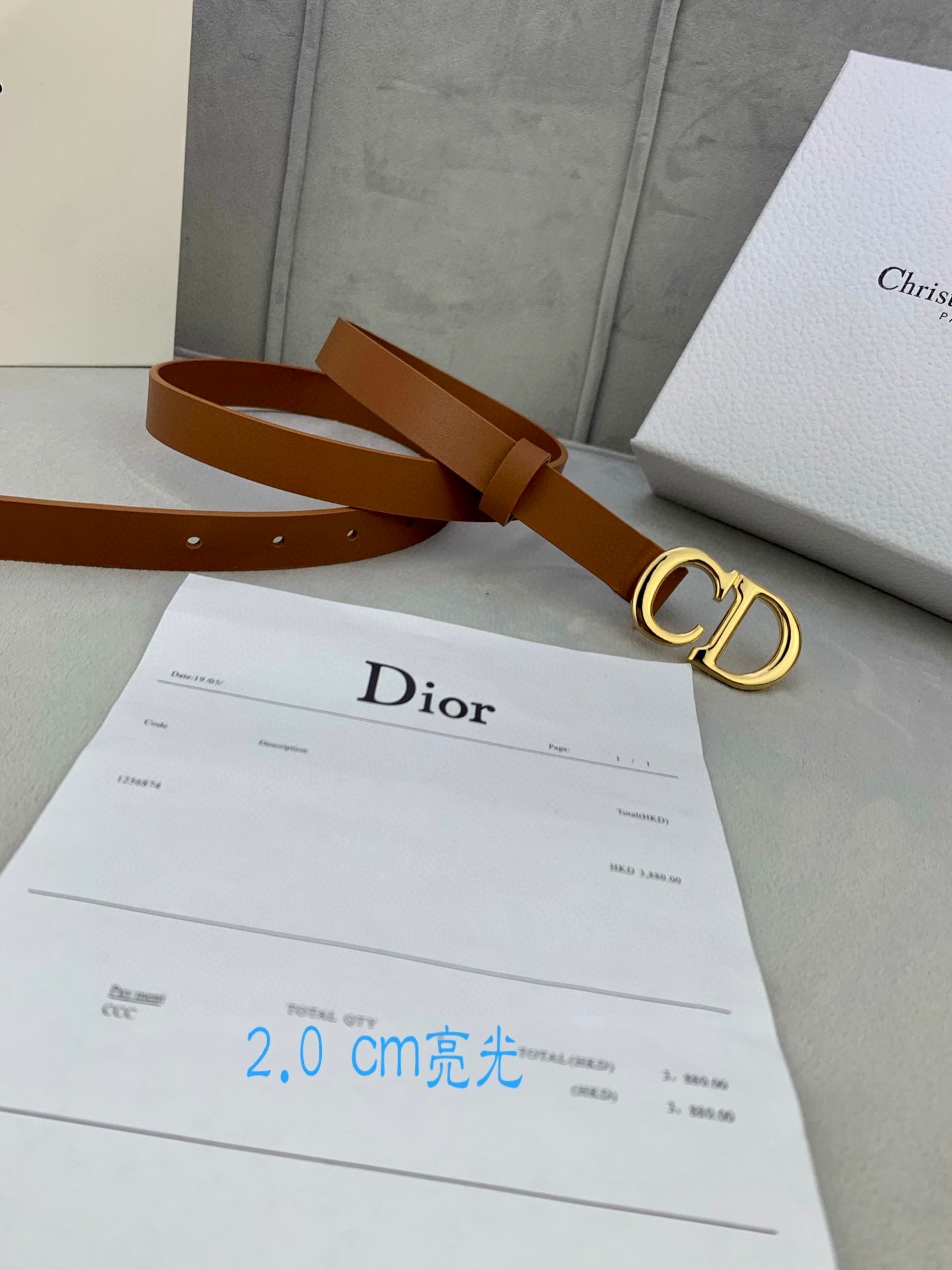 Tan leather belt with CD buckle over a Dior receipt card