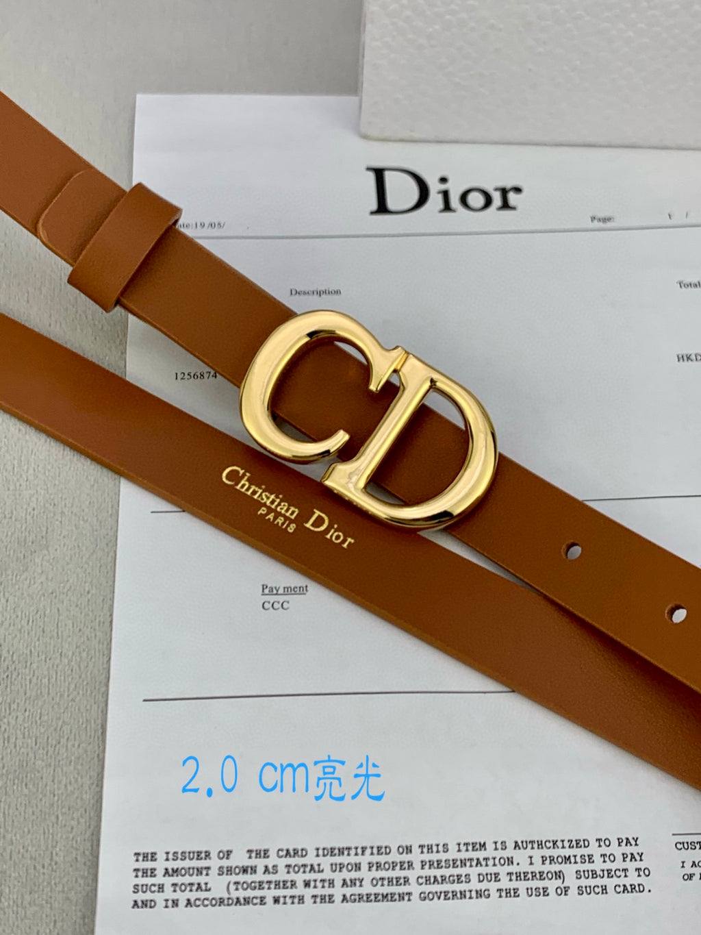 Tan leather belt with gold-tone CD buckle and rivet holes