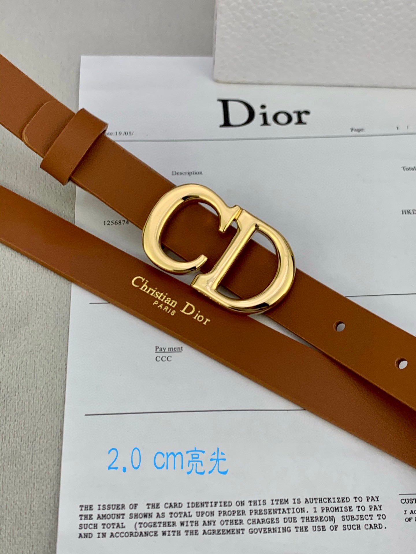 Tan leather belt with gold-tone CD buckle and rivet holes