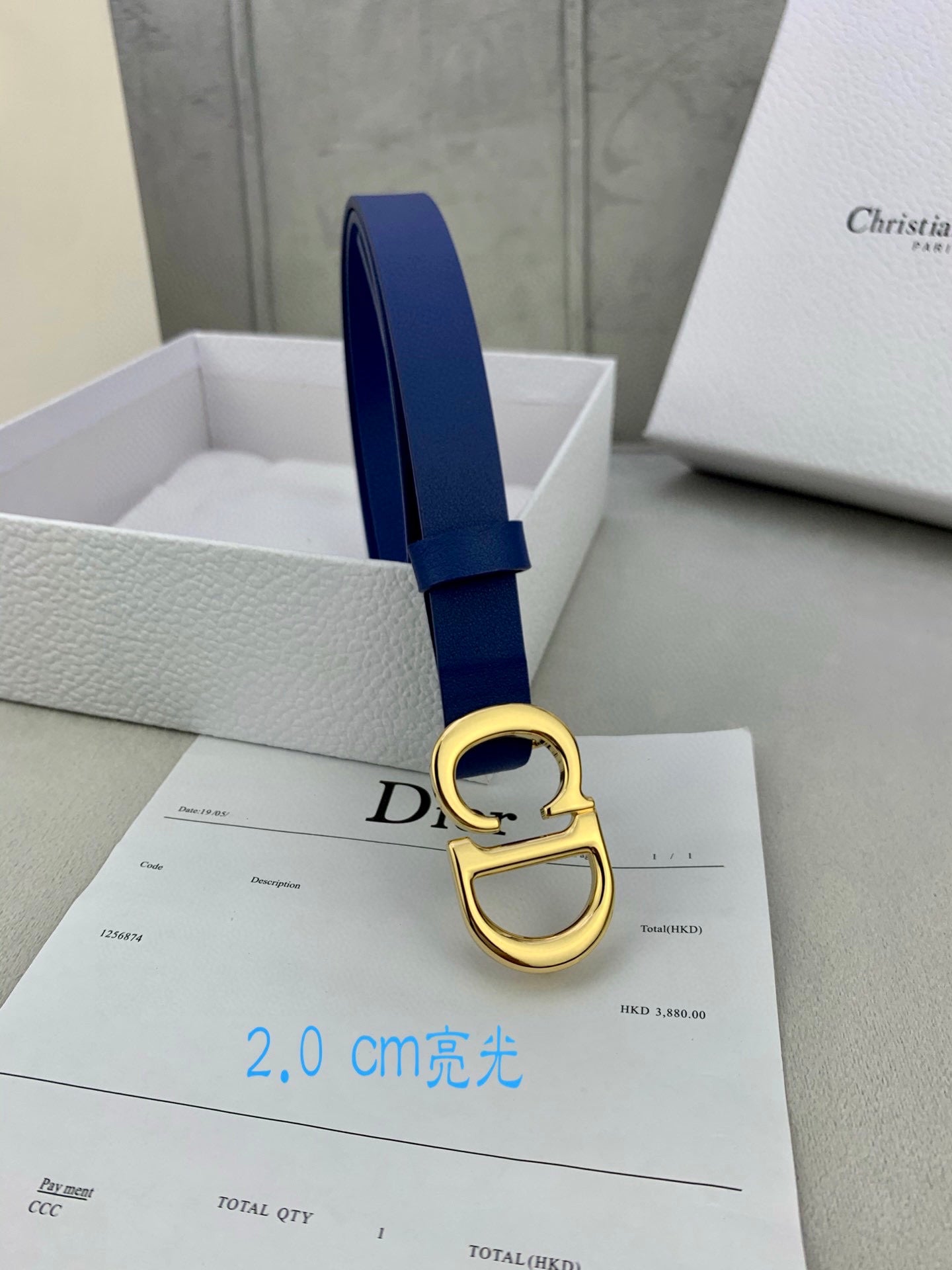 Blue Dior belt with gold-tone CD buckle, close-up on included card.