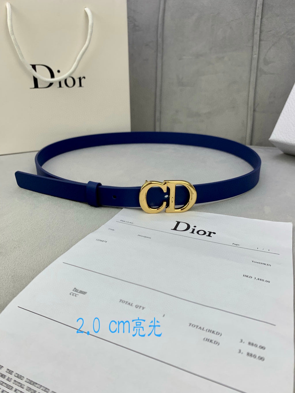 Blue Dior belt with CD logo buckle, shown laid flat on a surface.