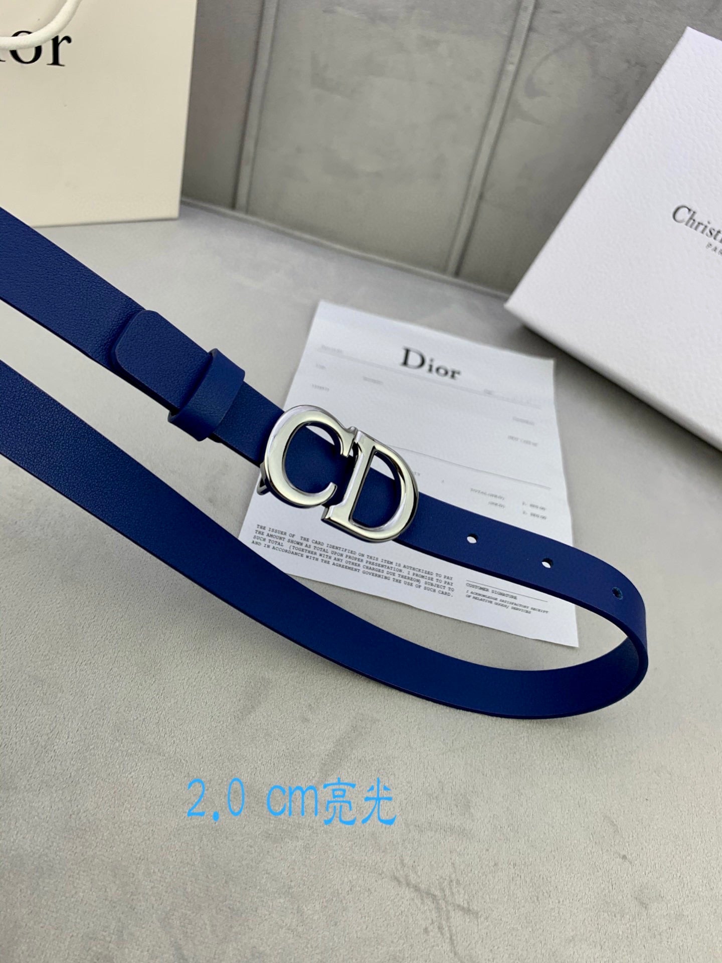 Blue Dior belt with CD logo buckle, laid out with included card.