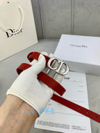 Dior red belt with CD buckle held in a white glove hand