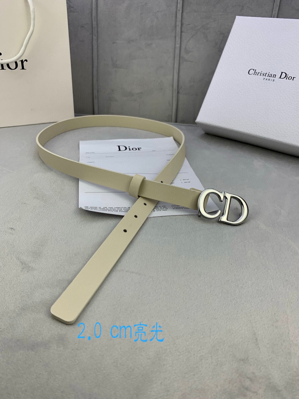 Beige belt with gold-tone CD buckle and long strap lay flat