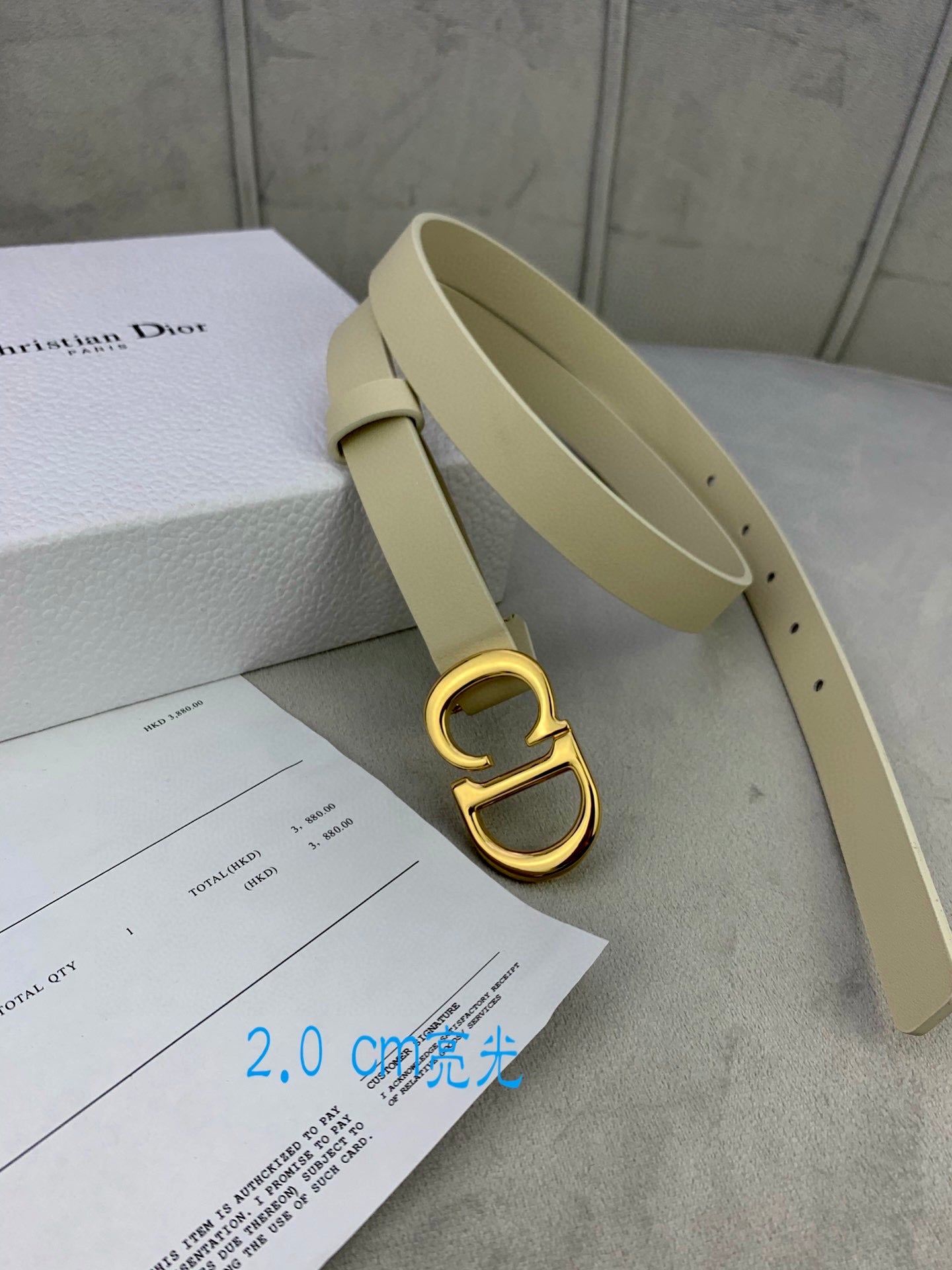 Beige belt with gold-tone CD buckle, open view of strap and belt holes