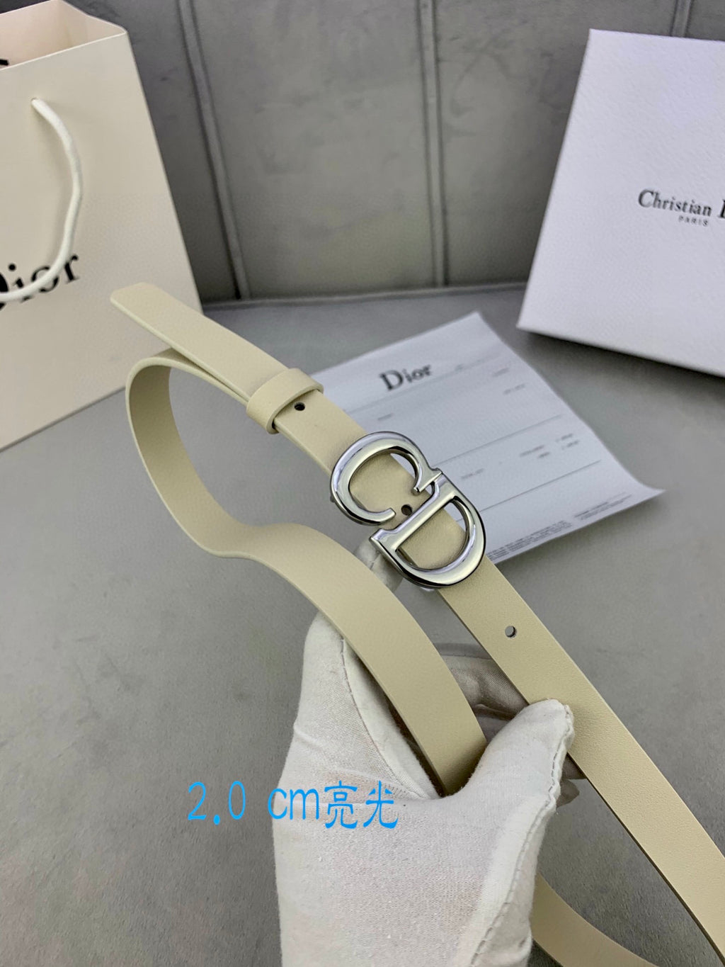 Beige leather belt with silver-tone CD buckle and adjustable strap holes