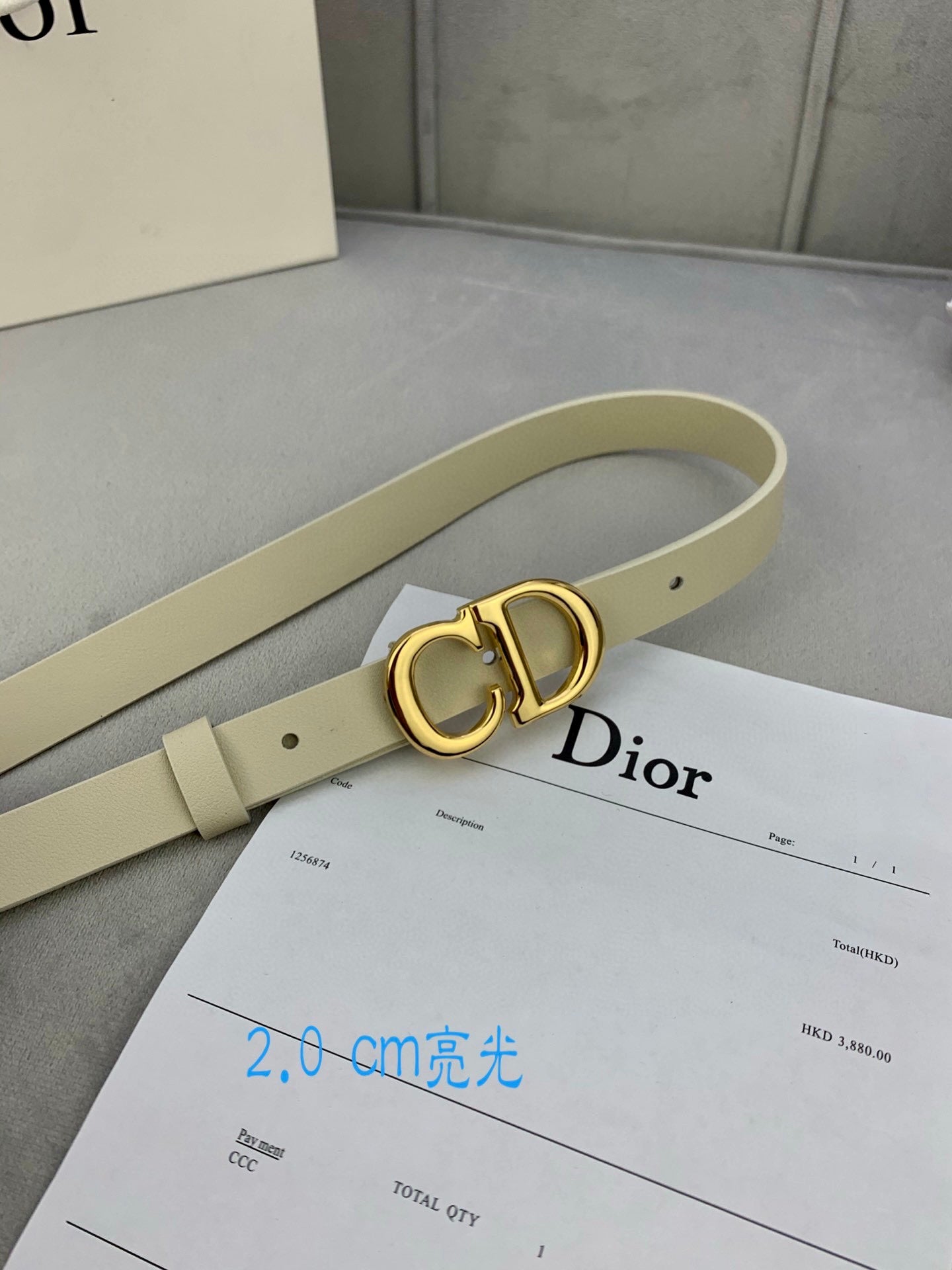 Light beige belt with gold-tone CD buckle and punched adjustment holes
