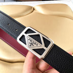 Prada belt with black pebbled leather, burgundy stripe, and silver logo buckle closeup