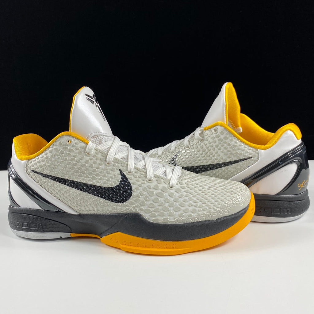 Nike basketball shoes with white textured upper, yellow collar, black swoosh, thick gray sole