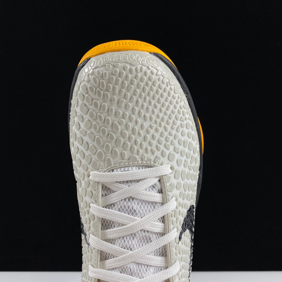 Nike basketball shoe toe view with white textured upper and white laces, yellow edge lining