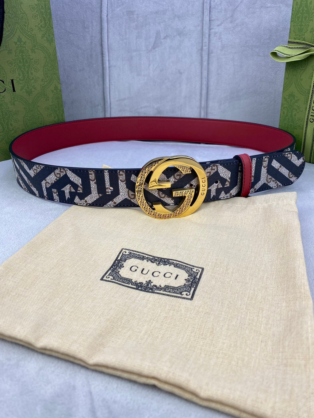 Gucci belt with navy and beige GG logo canvas strap, gold buckle and red lining.