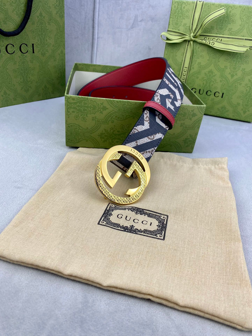 Gucci belt on box and dust bag, navy GG logo strap with red edge and gold buckle.