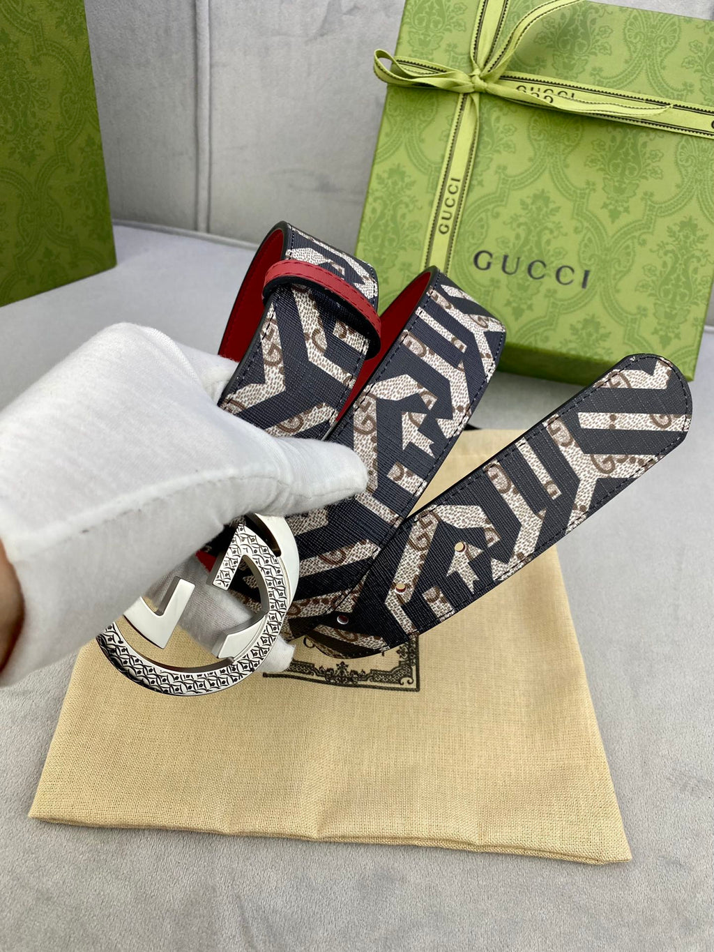 Gucci belt on dust bag, navy GG canvas strap with red lining and silver-toned buckle.