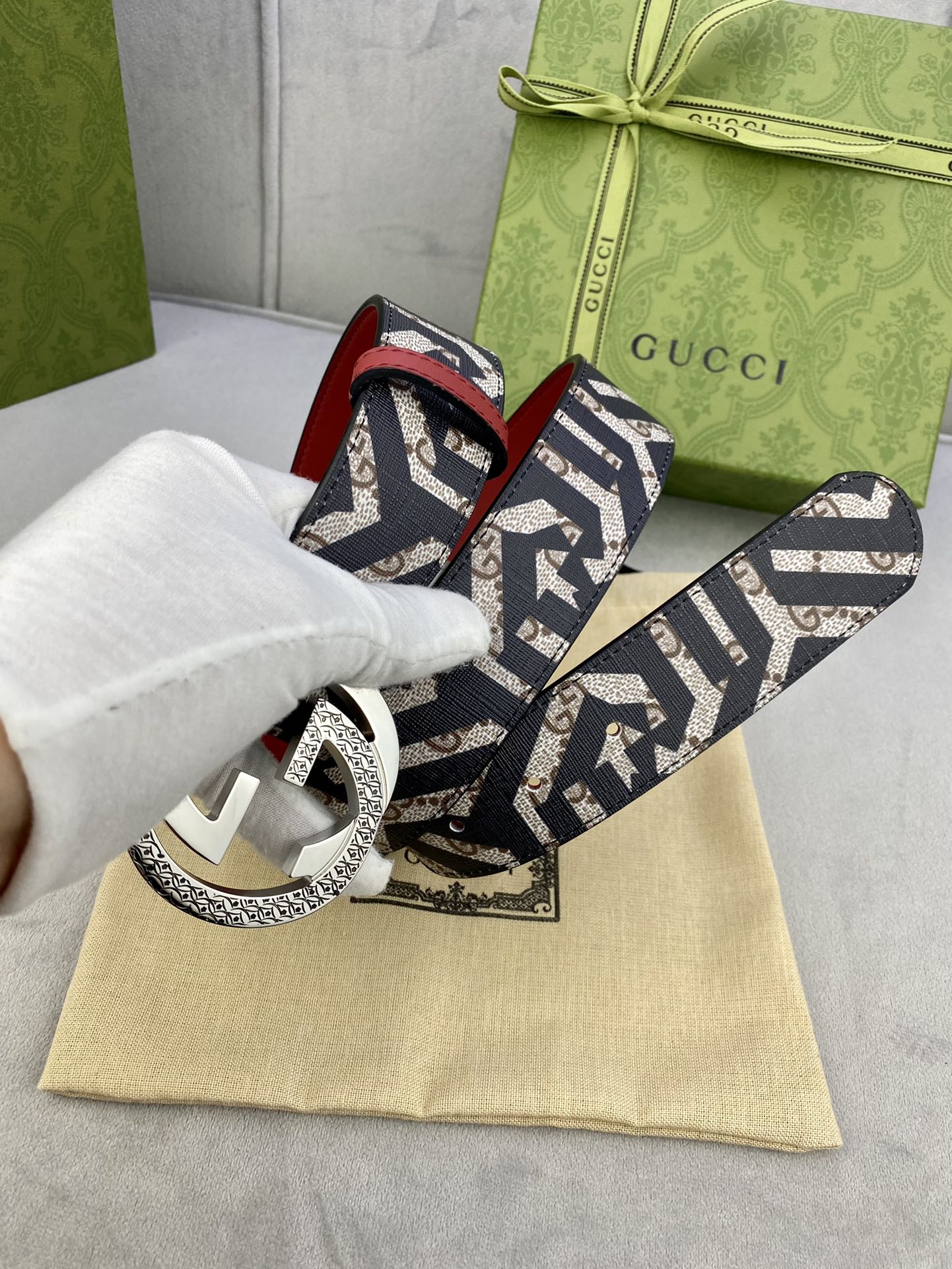 Gucci belt on dust bag, navy GG canvas strap with red lining and silver-toned buckle.