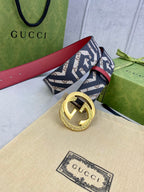 Gucci belt with navy GG logo strap, red leather strap back, gold round buckle and ring detail.