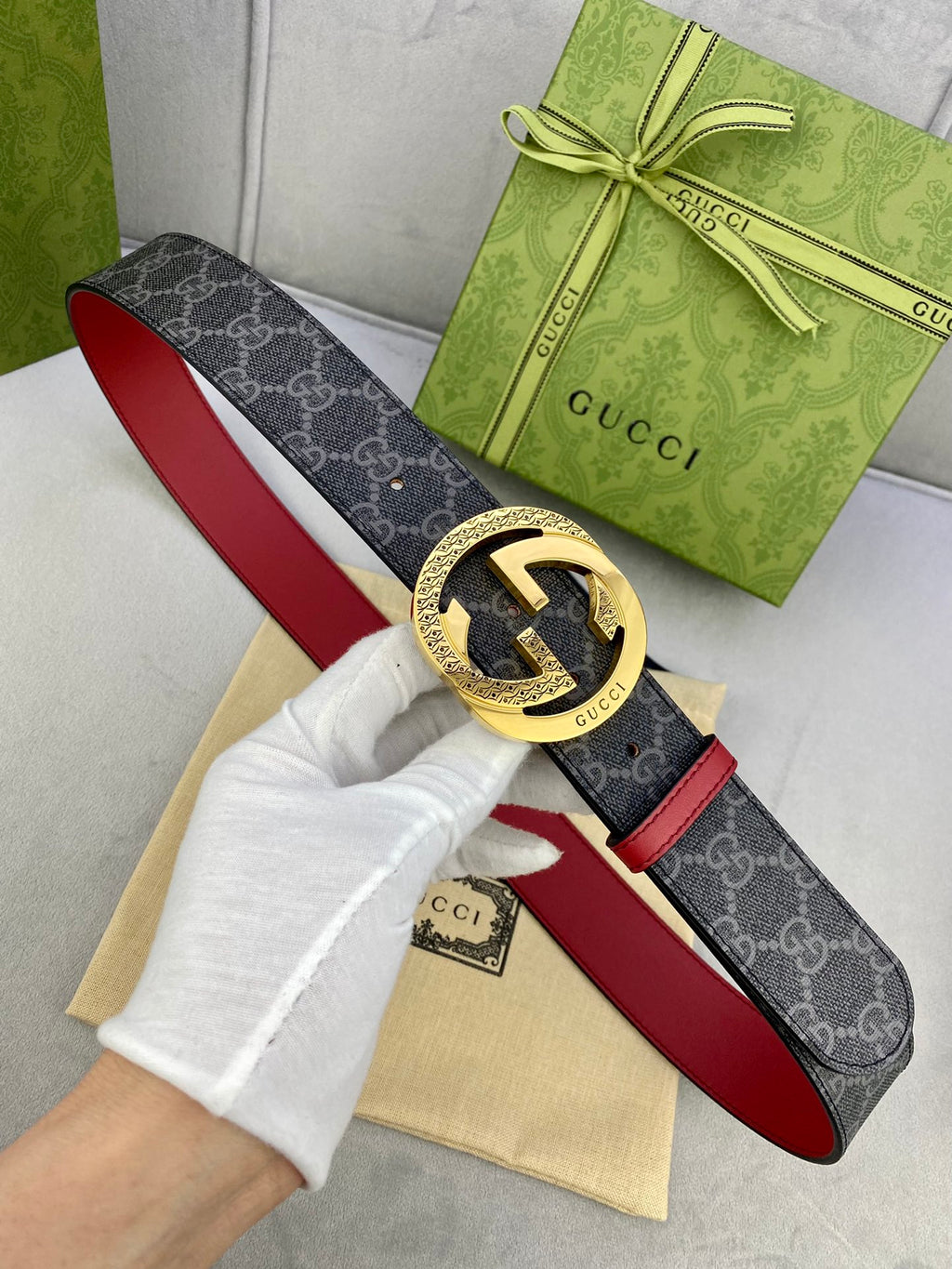 Gucci belt with gold-toned GG buckle: dark monogram strap, red leather lining.