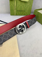 Gucci belt buckle close-up: silver-toned GG on dark monogram strap, red edge.
