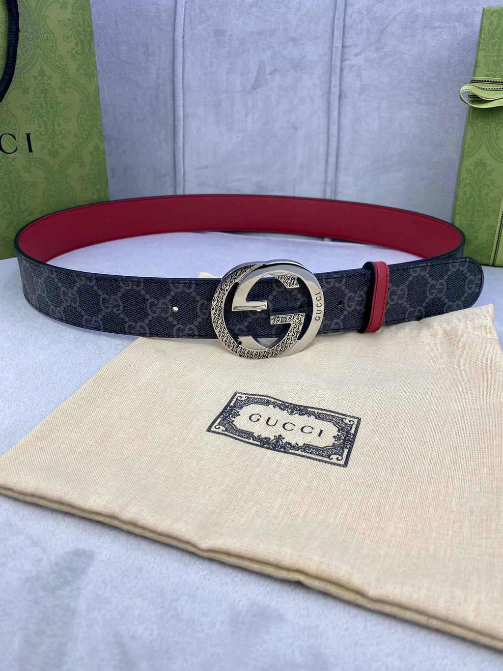 Gucci belt: dark monogram strap, red leather trim, silver round GG buckle.