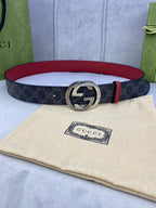 Gucci belt: dark monogram strap, red leather trim, silver round GG buckle.