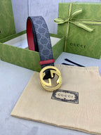 Gucci belt angled view: dark monogram strap, red inner, gold-toned GG buckle.
