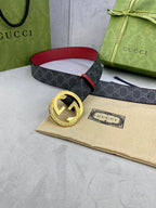 Gucci belt on cloth: dark monogram strap, red trim, gold-toned GG buckle.