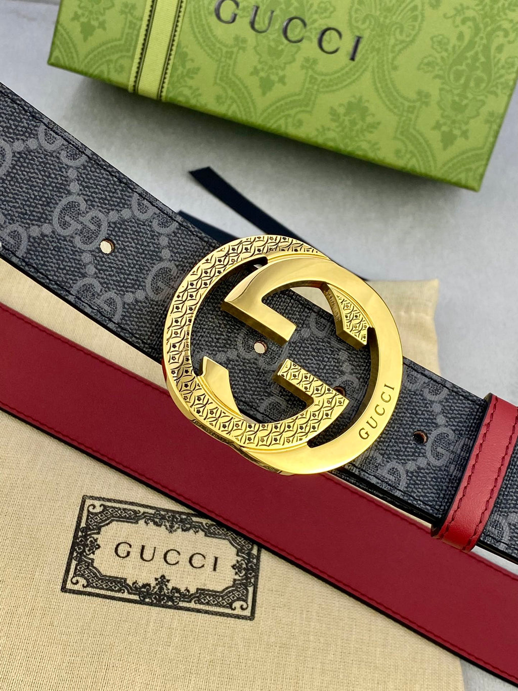 Gucci belt buckle close-up: gold-toned GG ring on dark monogram leather, red edge.