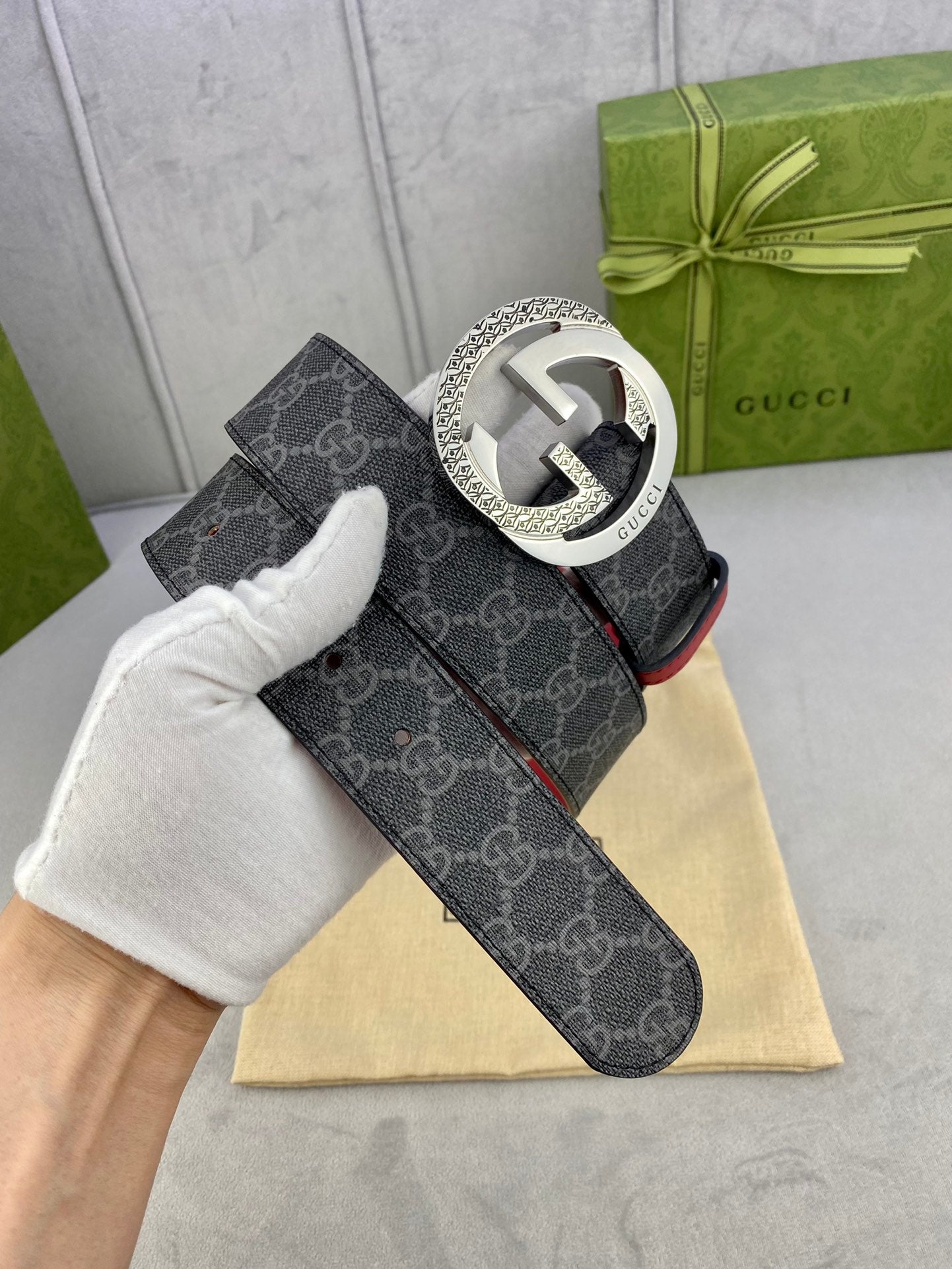 Gucci belt side view: dark monogram strap, red underside, large silver-toned GG buckle.