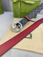 Gucci belt laid flat: dark monogram strap, red leather center, silver buckle with holes.