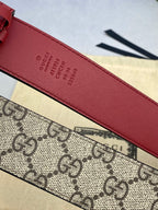 Gucci belt close-up of red leather strap with embossed Gucci text and numbers