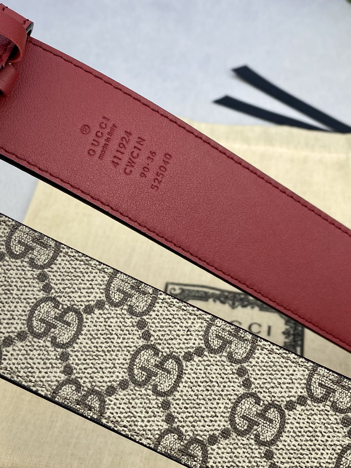 Gucci belt close-up of red leather strap with embossed Gucci text and numbers