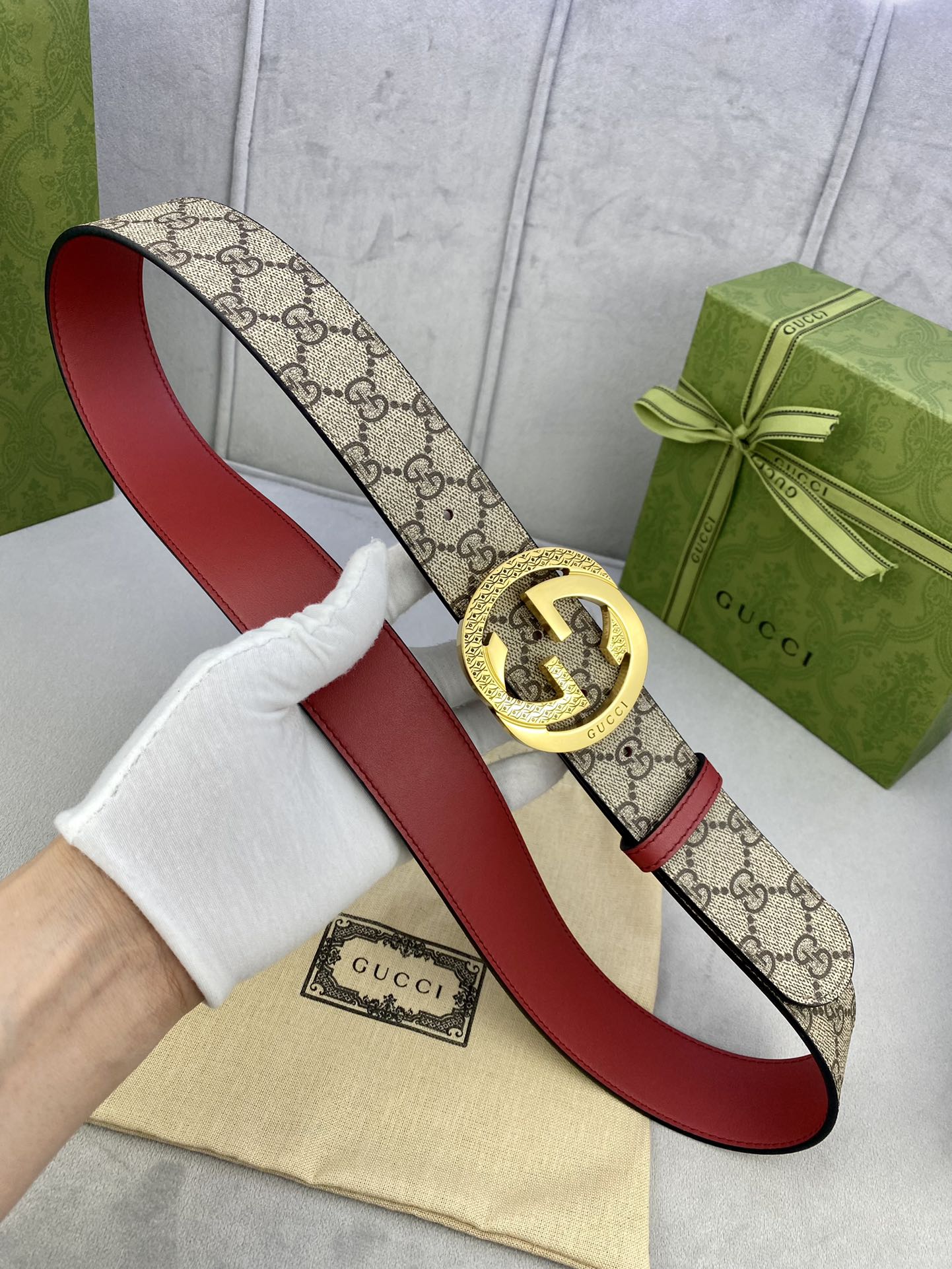 Gucci belt on display, beige GG canvas with red edges and gold buckle