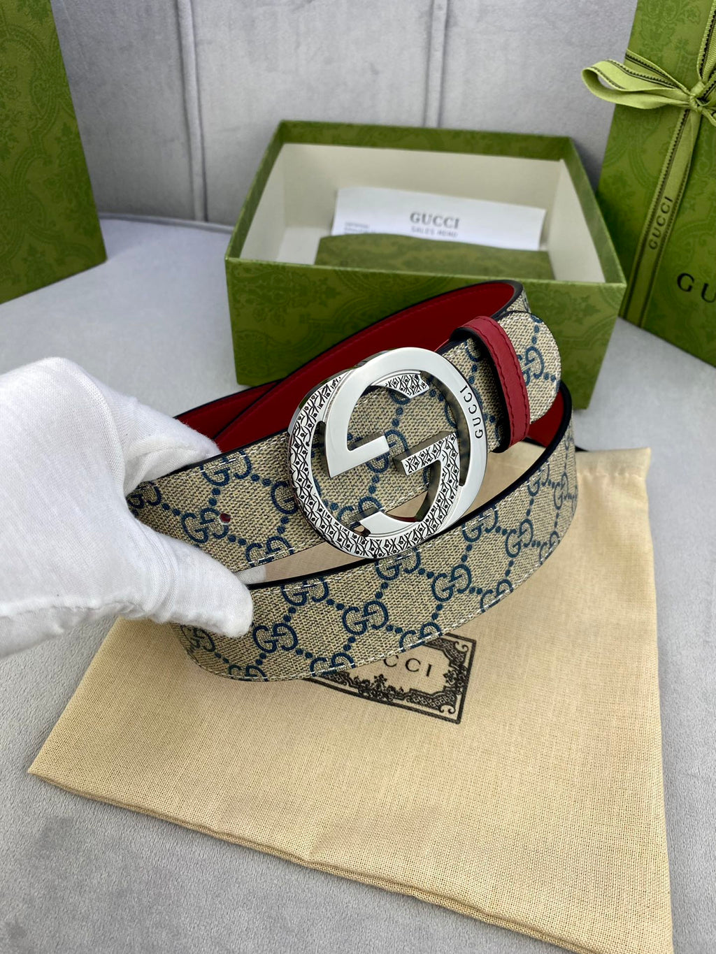 Logo-print belt with red leather trim and silver round buckle, partially in view