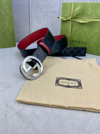 Gucci belt with dark monogram leather, red underside, and silver circular buckle