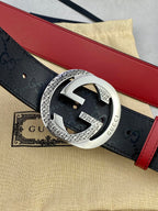 Gucci belt close-up with dark monogram strap, red edge, and silver buckle