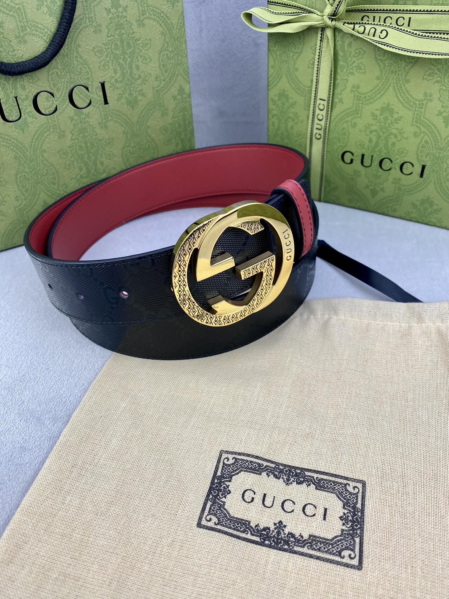 Gucci belt with dark textured leather, red trim, and gold round double G buckle
