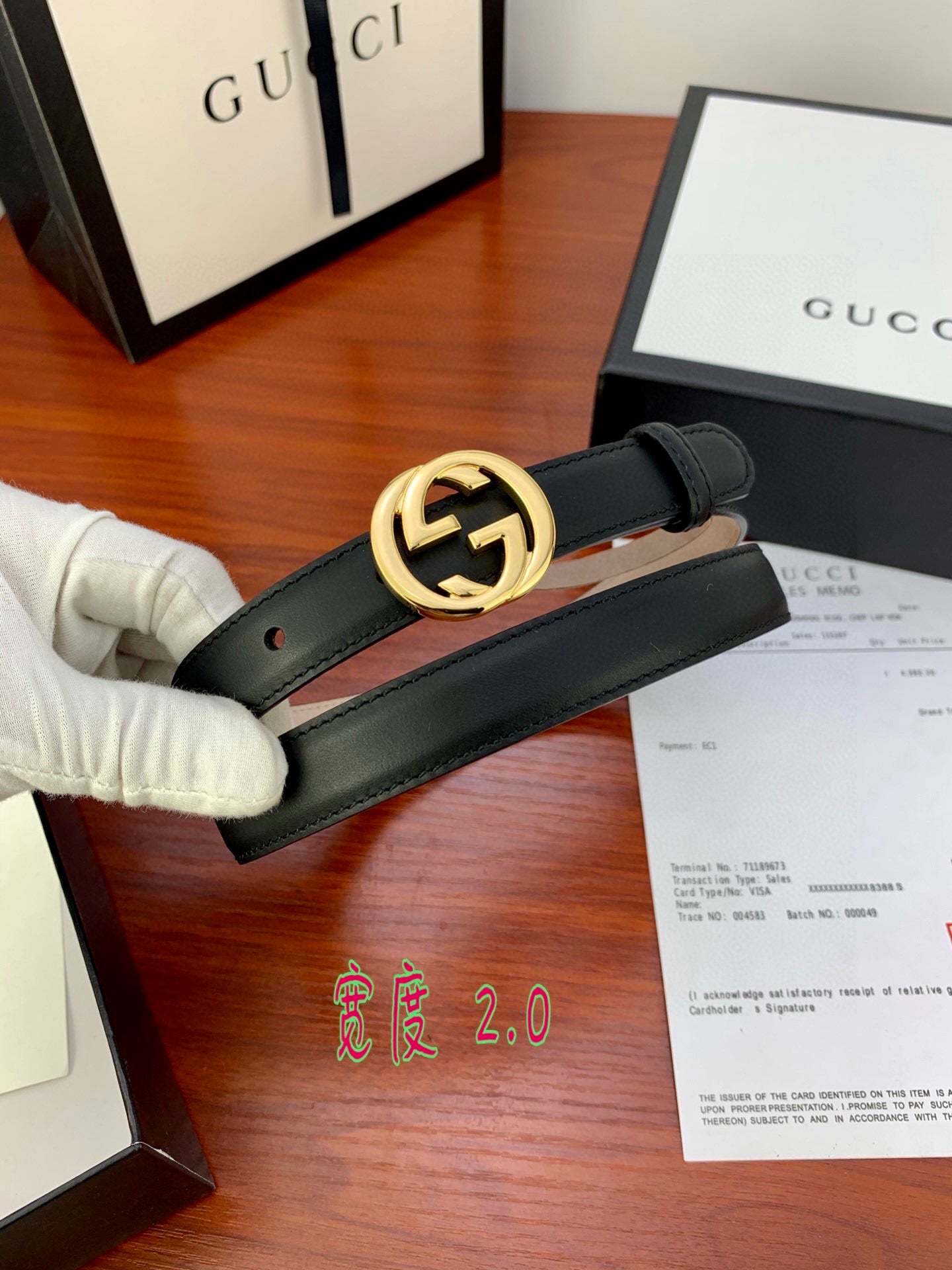 Gucci belt with dark leather strap and gold interlocking G buckle, close-up